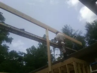 Carpenter setting a ridge beam over a new addition frame in Coker