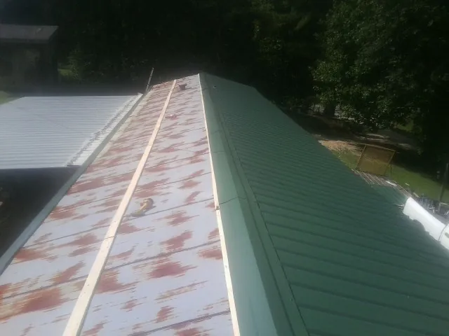 Old rusted panels beside newly installed green metal roofing — Wind Damage Roof Repair by Roofing Brothers in Coker