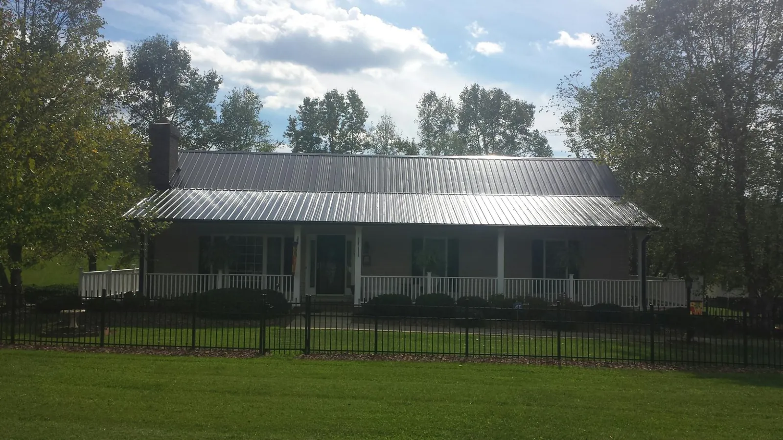 Gray metal roof on a brick ranch with a full width front porch — Gutter Guard Installation work by our crew in Coker