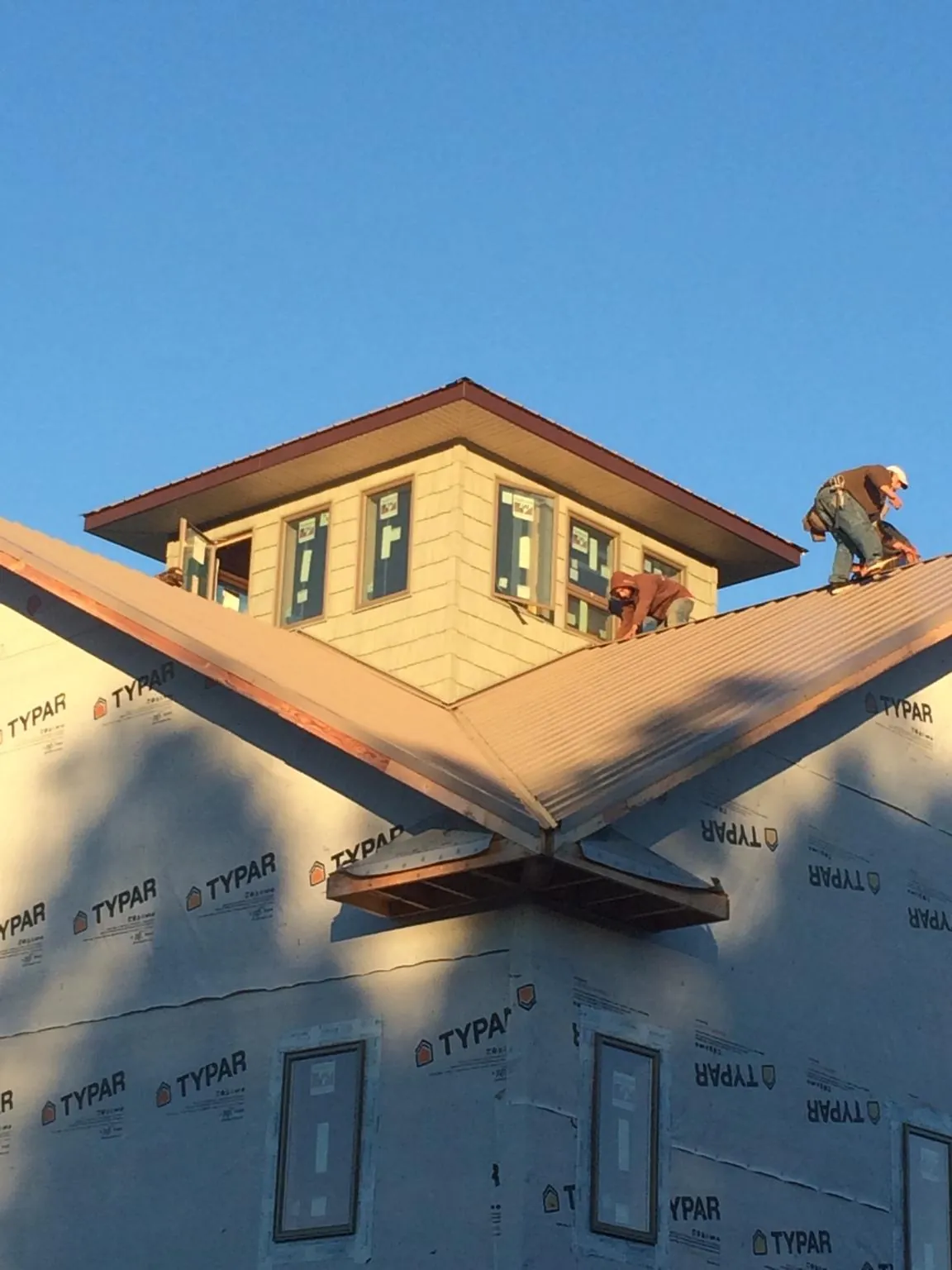 Roofers working around a rooftop cupola on a new metal roof at sunset — Roof Waterproofing in Coker by Roofing Brothers